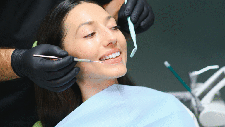 Dentist in black gloves examining a smiling female patient's teeth in a clinic.